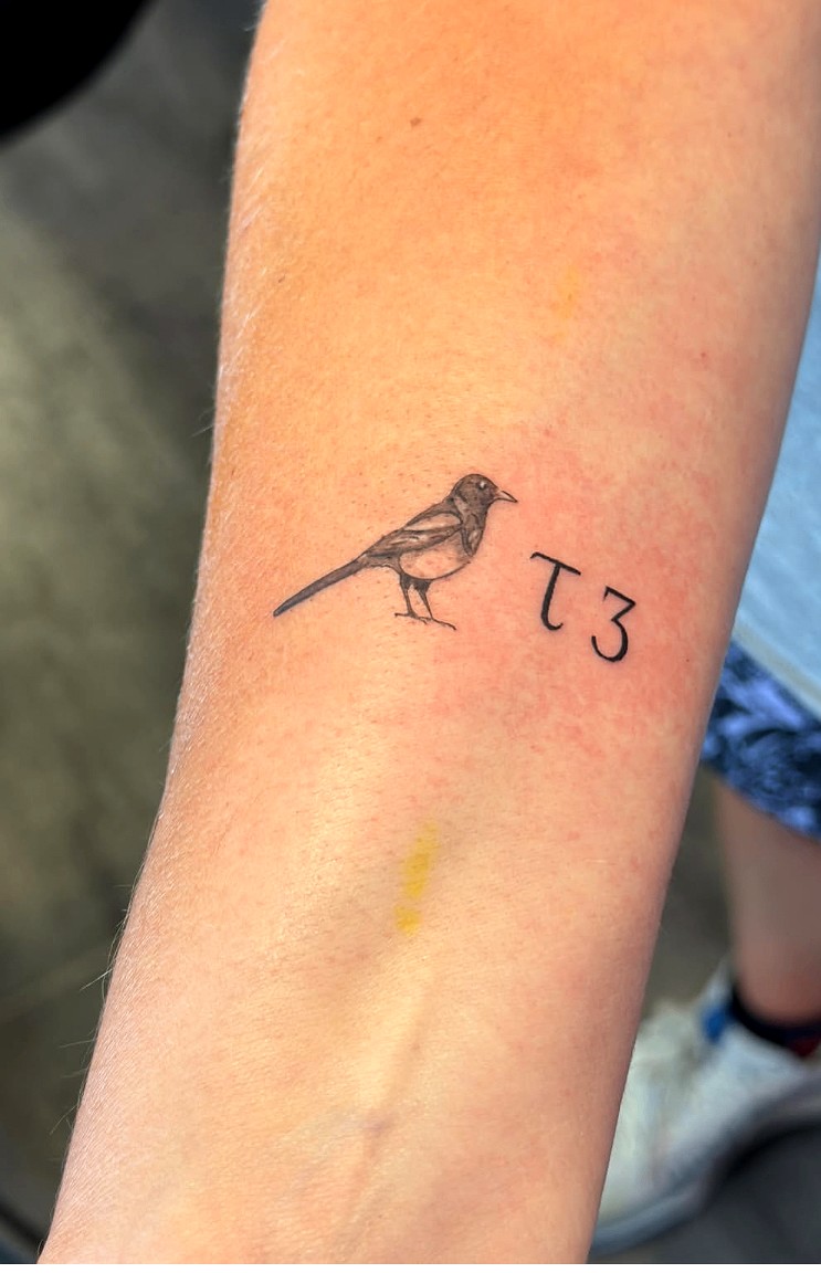 Delicate fine line magpie bird tattoo on the forearm