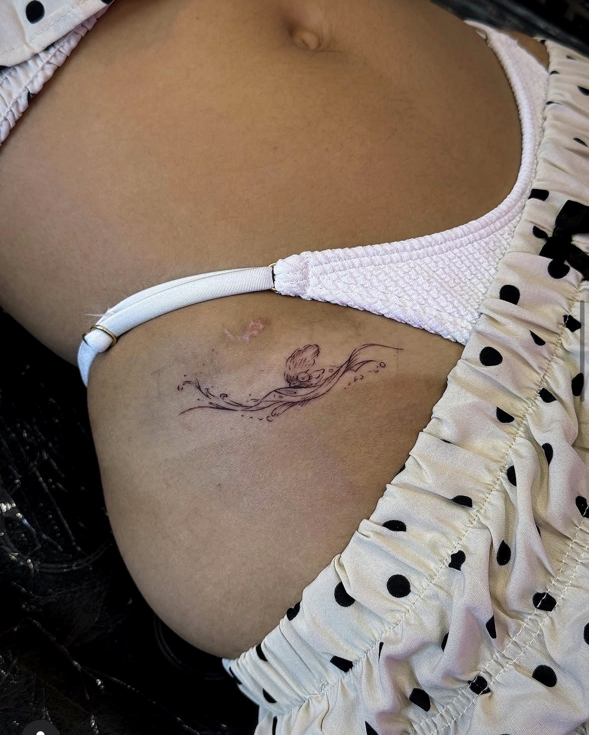 Delicate fine line shell and wave tattoo on the hip