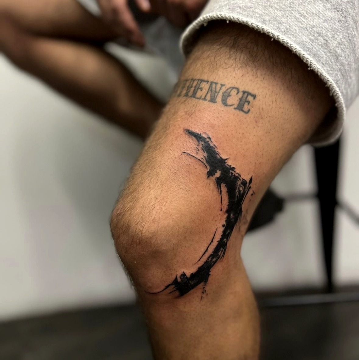 Abstract brushstroke tattoo on the knee