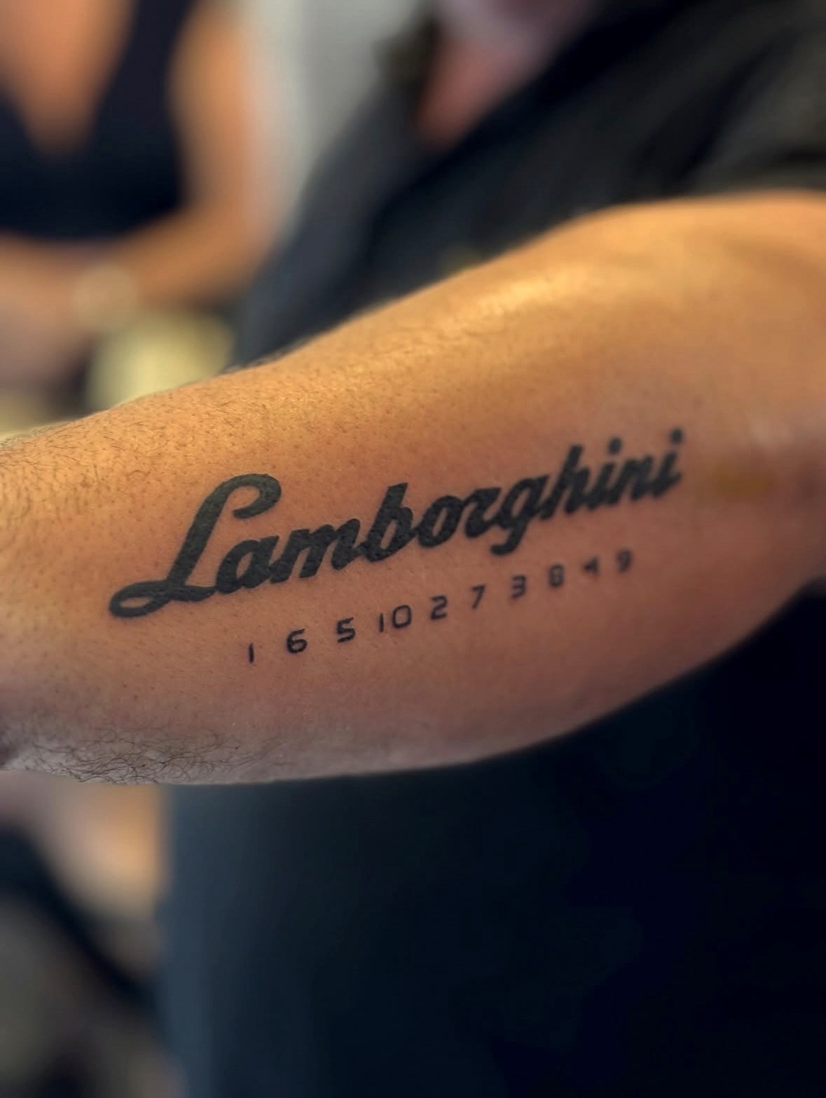Bold Lamborghini script lettering tattoo on the forearm